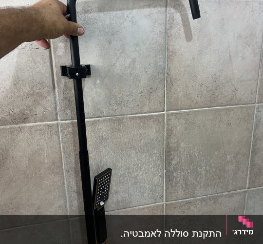 ברז מקלחת עם צינור זהב על קיר אריחים